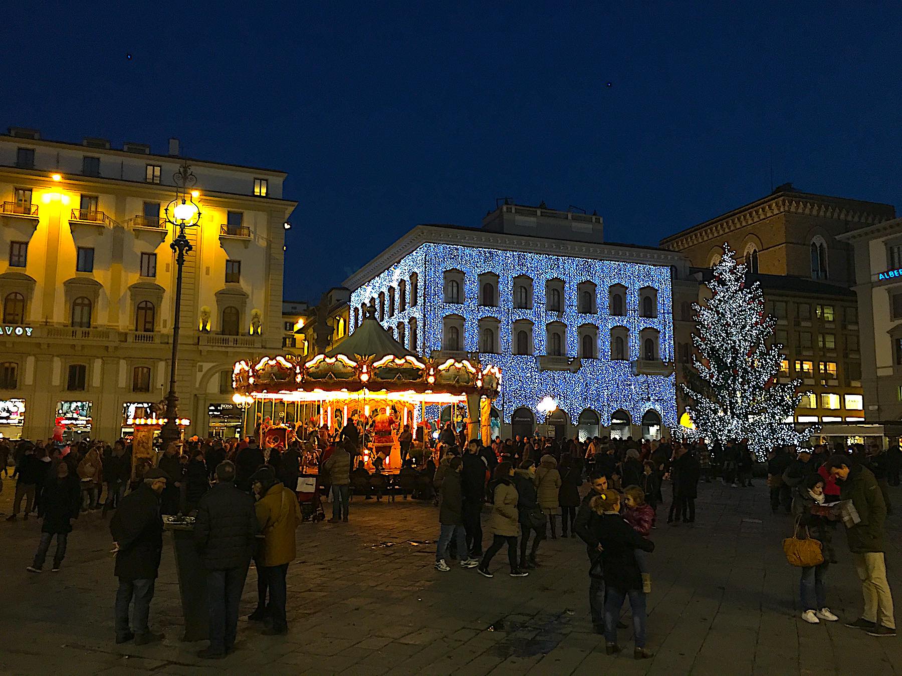 Piazza della Repubblica in festive splendor with the carousel lights twirling and La Rinascente aglow, Florence's Christmas spirit shines brigh