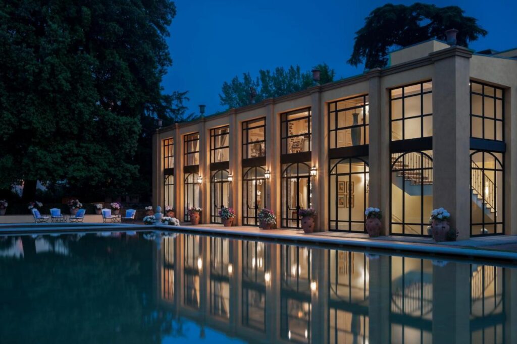 The 7 Best Luxury Hotels in Florence 12 Outdoor pool at Four Seasons Hotel Firenze at night, with modern glass architecture reflecting on the water.