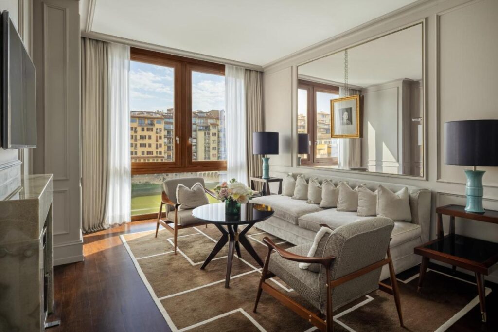 The 7 Best Luxury Hotels in Florence 27 Prestige Suite at Portrait Firenze with spacious living area, large windows, and stunning views of the Arno River and Ponte Vecchio.
