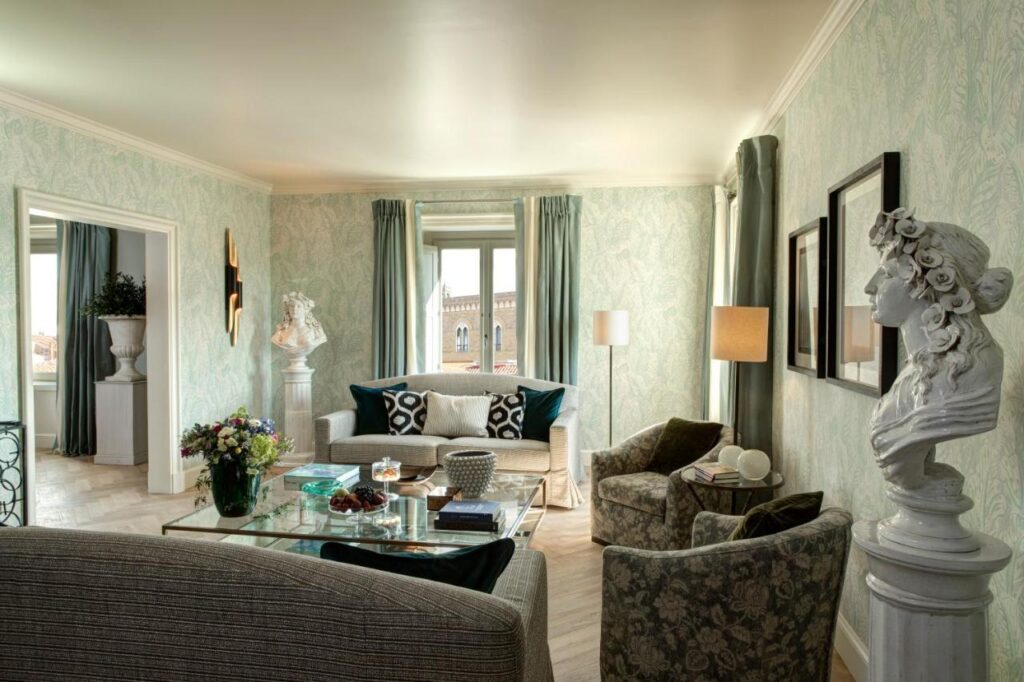 The 7 Best Luxury Hotels in Florence 7 Stylish hotel suite with pastel green wallpaper, modern and classical decor, and a bust sculpture