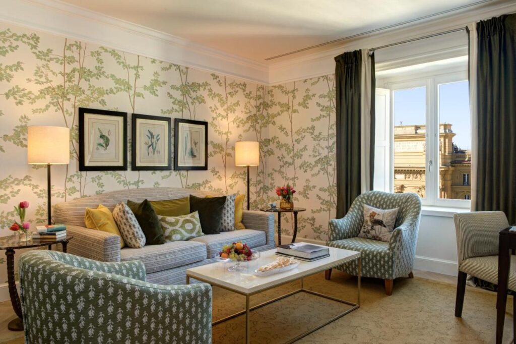 The 7 Best Luxury Hotels in Florence 8 Bright sitting area with striped sofa, patterned armchairs, and a window overlooking Piazza della Repubblica in Florence.