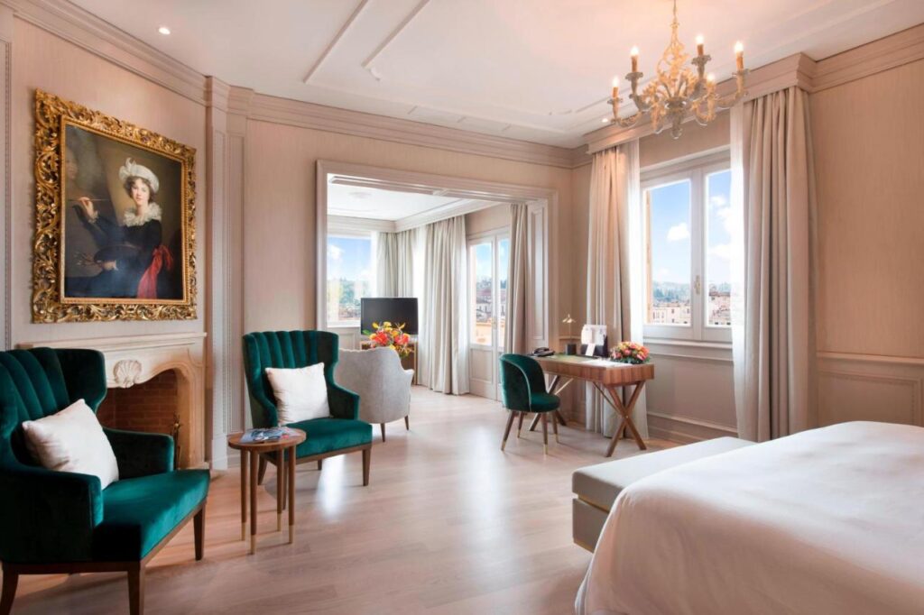 The 7 Best Luxury Hotels in Florence 34 Spacious suite at The Westin Excelsior Florence with green armchairs, ornate fireplace, and large windows overlooking the city.