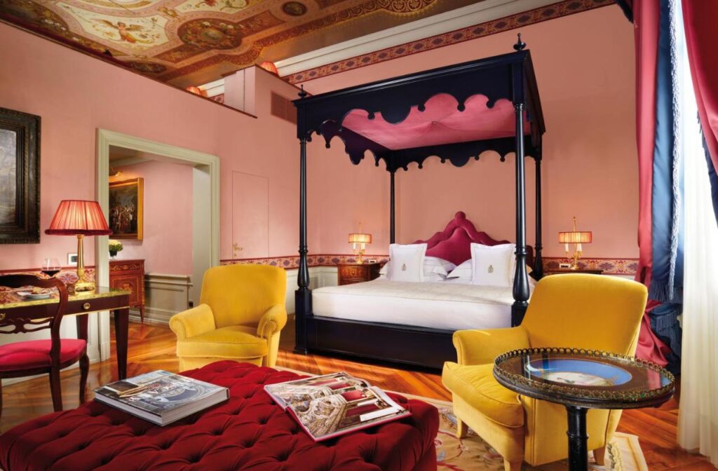 The 7 Best Luxury Hotels in Florence 22 Elegant room at Villa Cora with yellow armchairs, red velvet accents, and ornate painted ceiling.