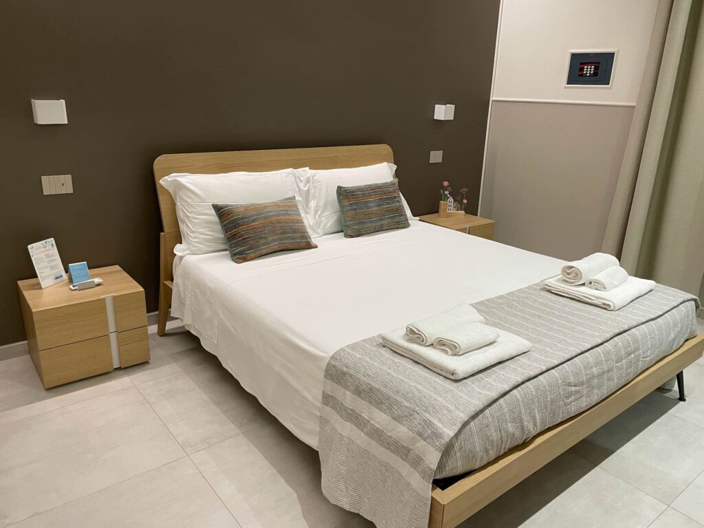 Where to Stay in Follonica: B&B Oltremare, a Top Choice on the Tuscan Coast 1 Modern double room at B&B Oltremare in Follonica with clean, minimalist decor and fresh towels prepared on the bed.