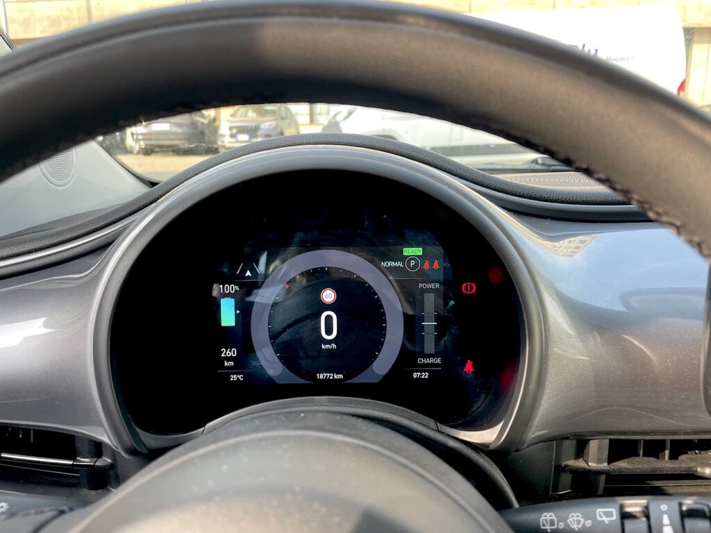  Digital dashboard of a Fiat 500 electric showing 100% battery, 260 km range, and 0 km/h speed. - Electric car rental in Tuscany 