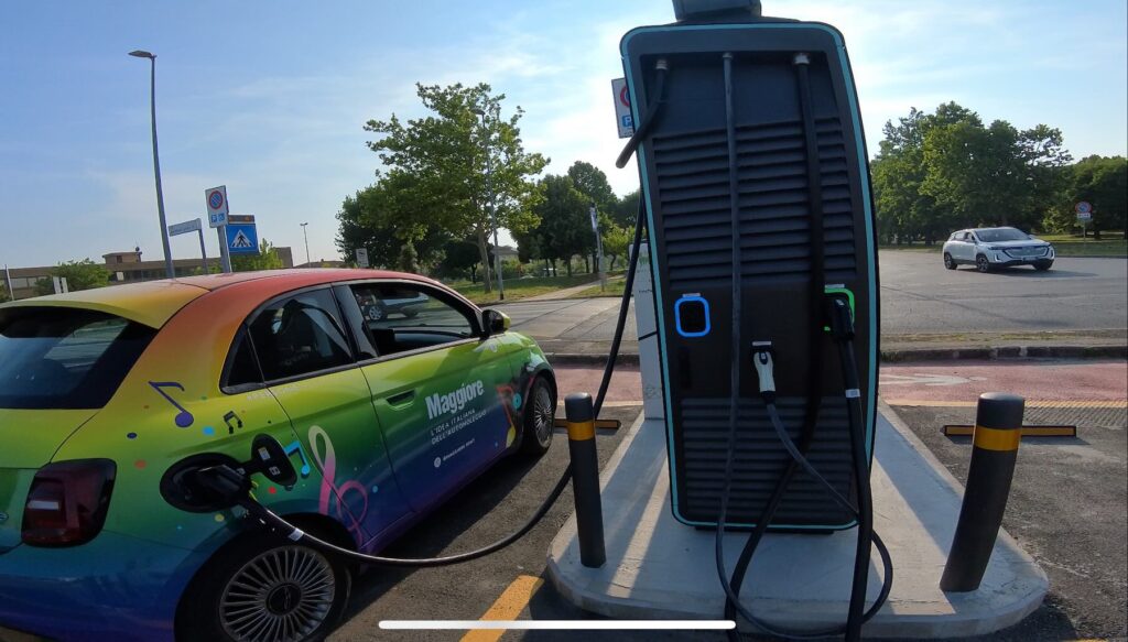 Colorful electric Fiat 500 plugged into a working charging station in Colle Val d’Elsa, Tuscany.