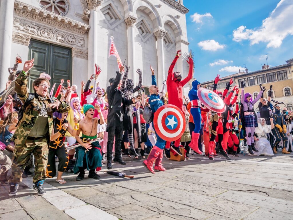 Group of cosplayers celebrating in front of a historic church during Lucca Comics & Games in Tuscany.
