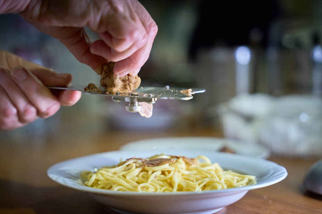Slicing white truffle over a plate of fresh pasta in Tuscany.