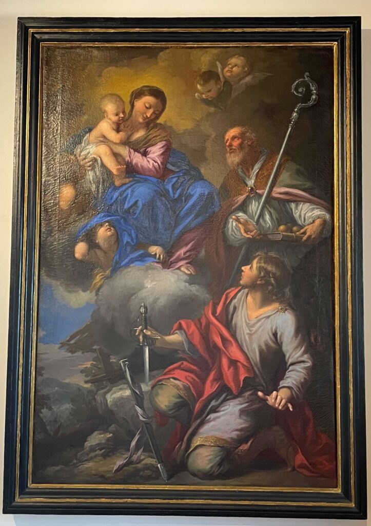 Painting by Gabbiani showing the Virgin Mary with Baby Jesus, Saint Galgano with the sword in the stone, and Saint Nicholas with his staff and three golden balls.