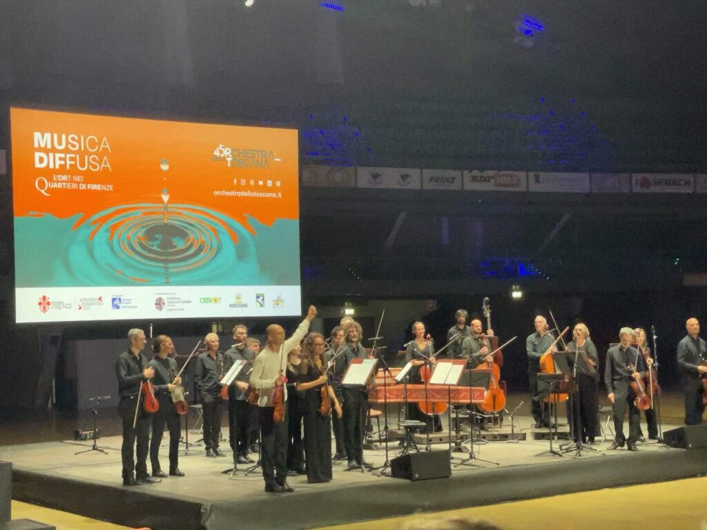 The Orchestra della Toscana on stage at the Nelson Mandela Forum in Florence, with conductor and violinist Giacomo Bianchi raising his bow to thank the audience during the Musica Diffusa concert featuring Vivaldi’s The Four Seasons.