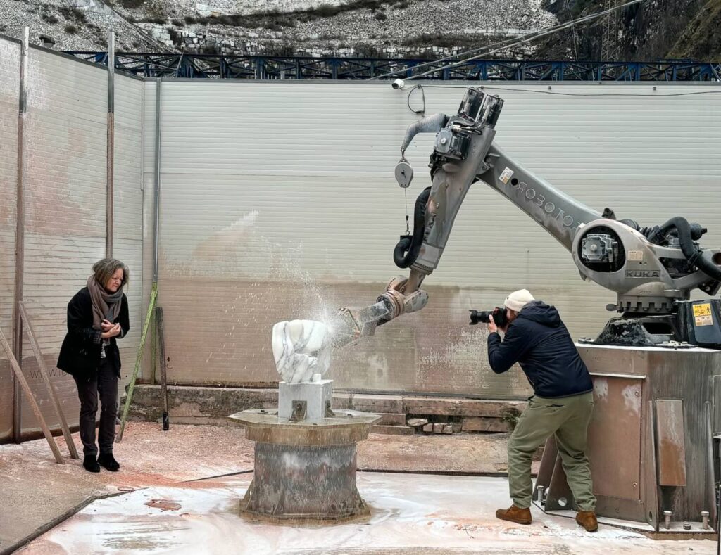 The Idea of Sculpture in Tuscany: book presentation in Pietrasanta 1 Robotic arm sculpting marble while artist Helena Bacardi observes, representing the dialogue between craftsmanship, innovation, and Tuscan artistic tradition.