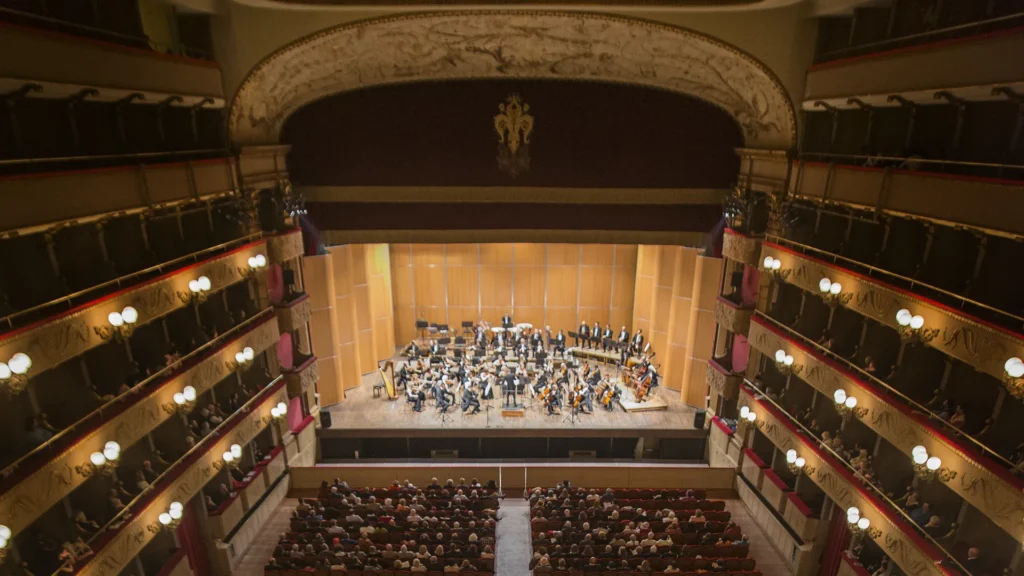 Christmas Concert in Florence 2025: Classical Music at Teatro Verdi on Christmas Eve 1 Interior view of Teatro Verdi in Florence with the Orchestra della Toscana performing on stage, seen from the audience, featuring the historic balconies and elegant theater architecture.
