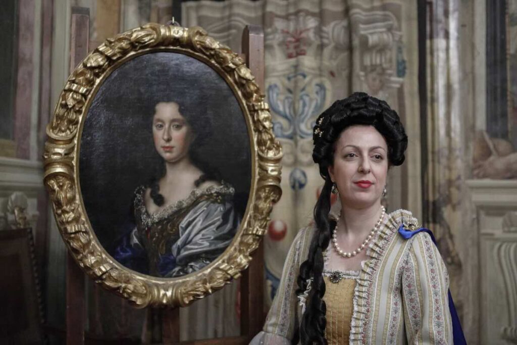 The Legacy of the Last Medici: Free Museums in Florence on Feb 18 2 Actress Giaele Monaci dressed in an 18th-century gown standing next to a framed oil portrait of Anna Maria Luisa de' Medici at the Palazzo Vecchio museum.