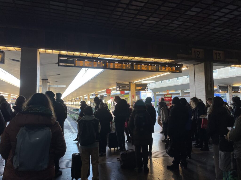 Rome to Florence Trains Suspended in April: Alternatives for Travelers 1 Rome to Florence Trains Suspended in April: Alternatives for Travelers - People waiting with suitcases on the platforms at Firenze Santa Maria Novella train station, beneath departure boards and platform signs, during a busy travel period.