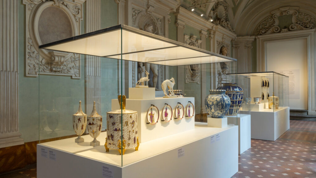 Decorative ceramic pieces displayed in glass cases at the Firenze Déco exhibition inside Palazzo Medici Riccardi in Florence