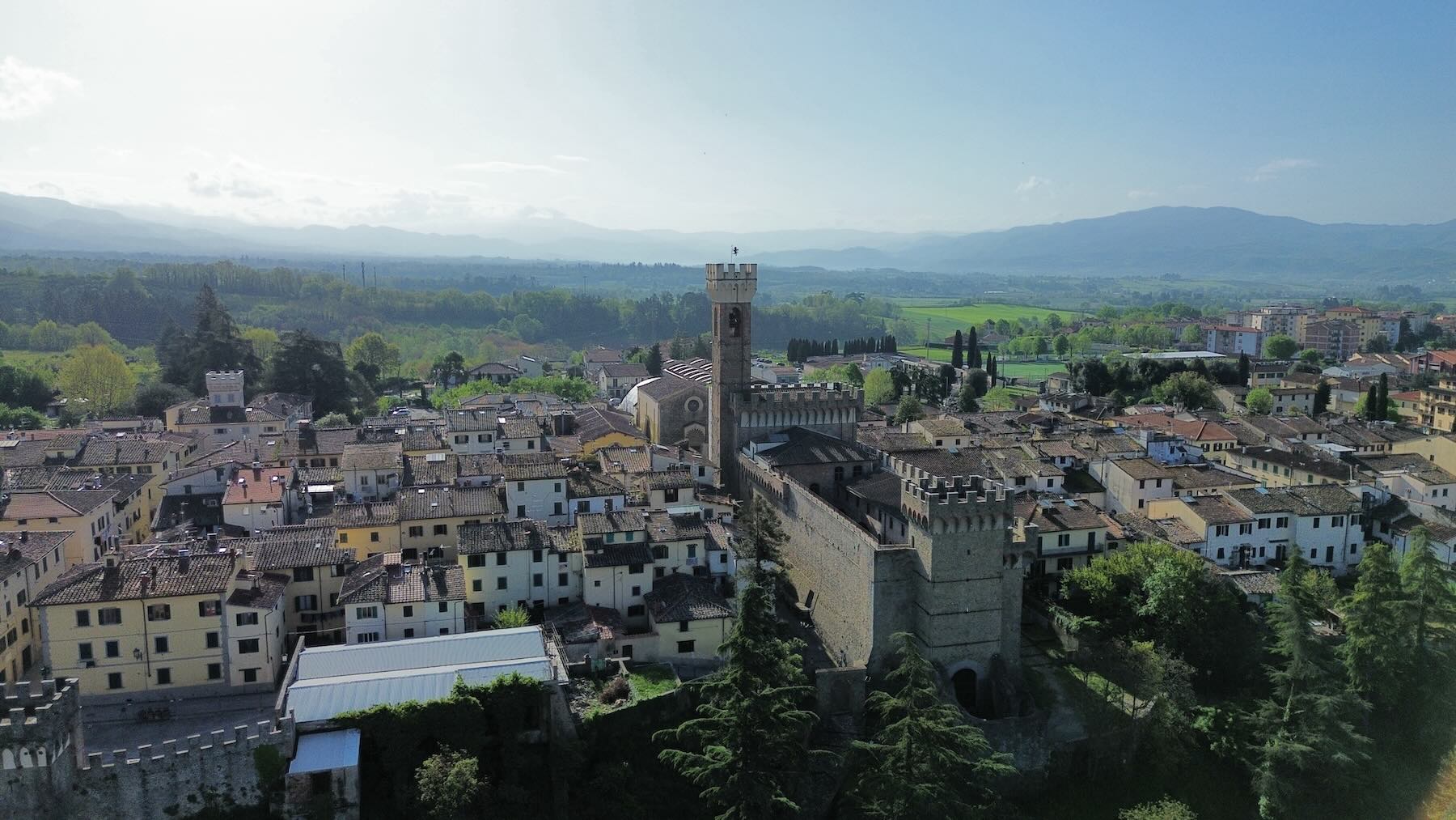 Drone view of Scarperia in Tuscany with the Palazzo dei Vicari, tiled rooftops, and the Mugello hills in the background