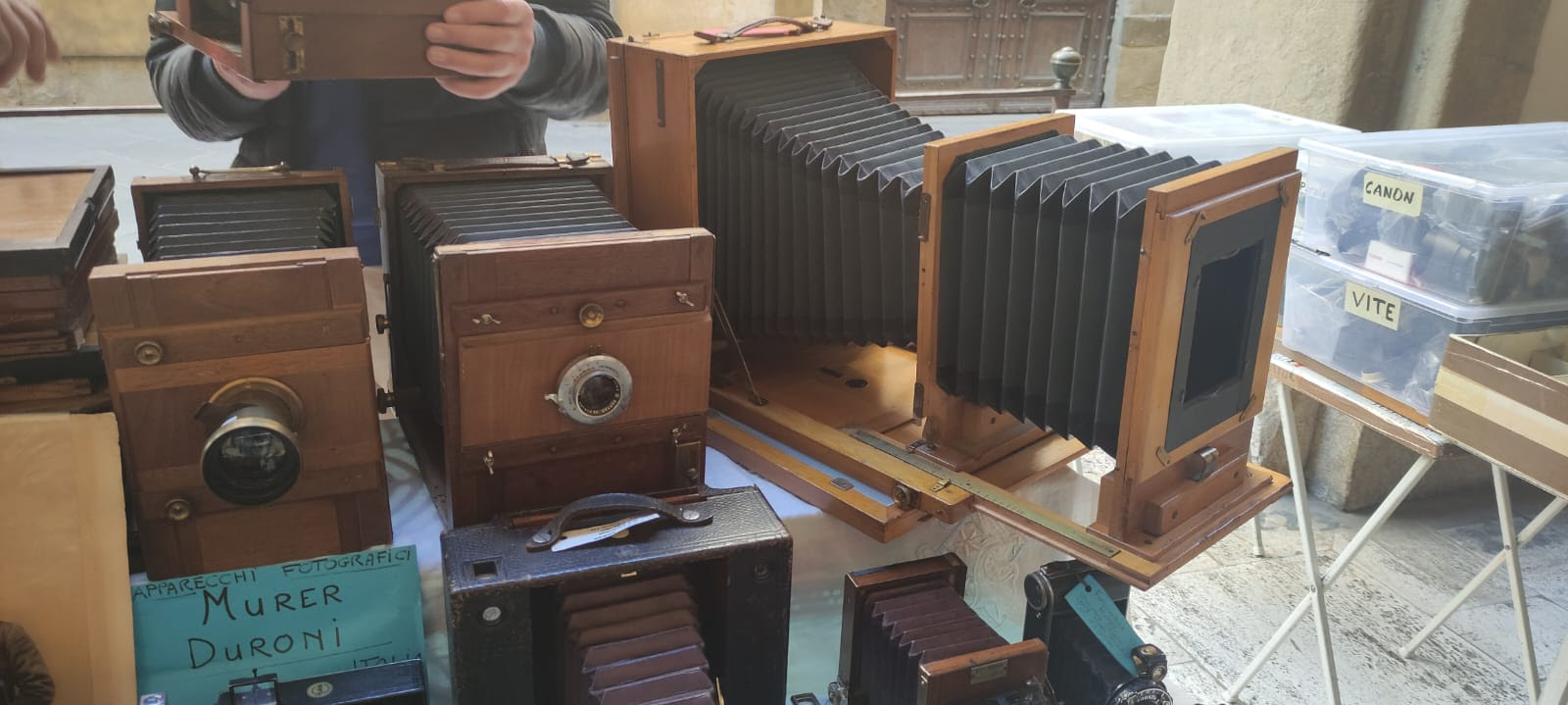 A selection of antique wooden cameras with bellows displayed on a table at Foto Antiquaria in Arezzo.