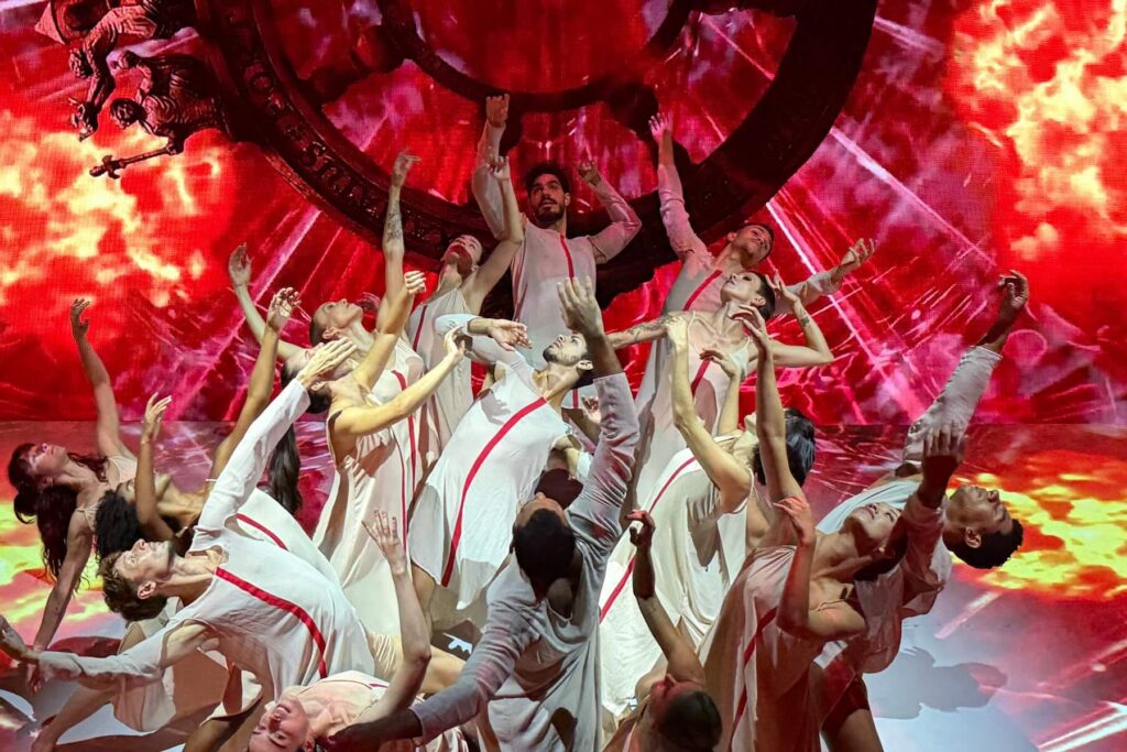 Florence Dance Festival 2026: When Dance Takes Over Florence’s Summer Nights 1 Vortice Dance Company dancers performing Carmina Burana with white costumes and red stage projections for the Florence Dance Festival 2026.