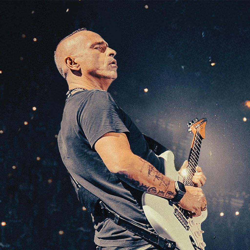 Eros Ramazzotti in Florence 2027: Tickets, Prices, and Concert Guide 1 Eros Ramazzotti playing a white electric guitar onstage